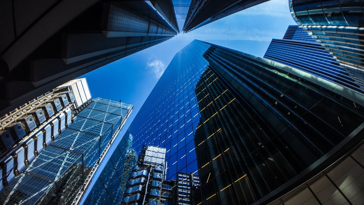 Modern glass office building exterior with tree and sky reflection