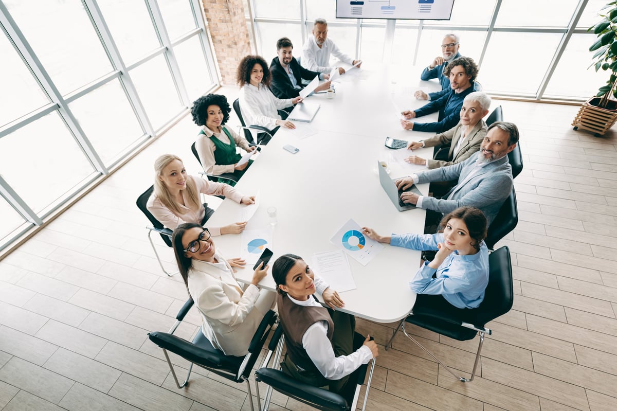 A diverse group of professionals engaged in a meeting around a large table in a polished modern office setting